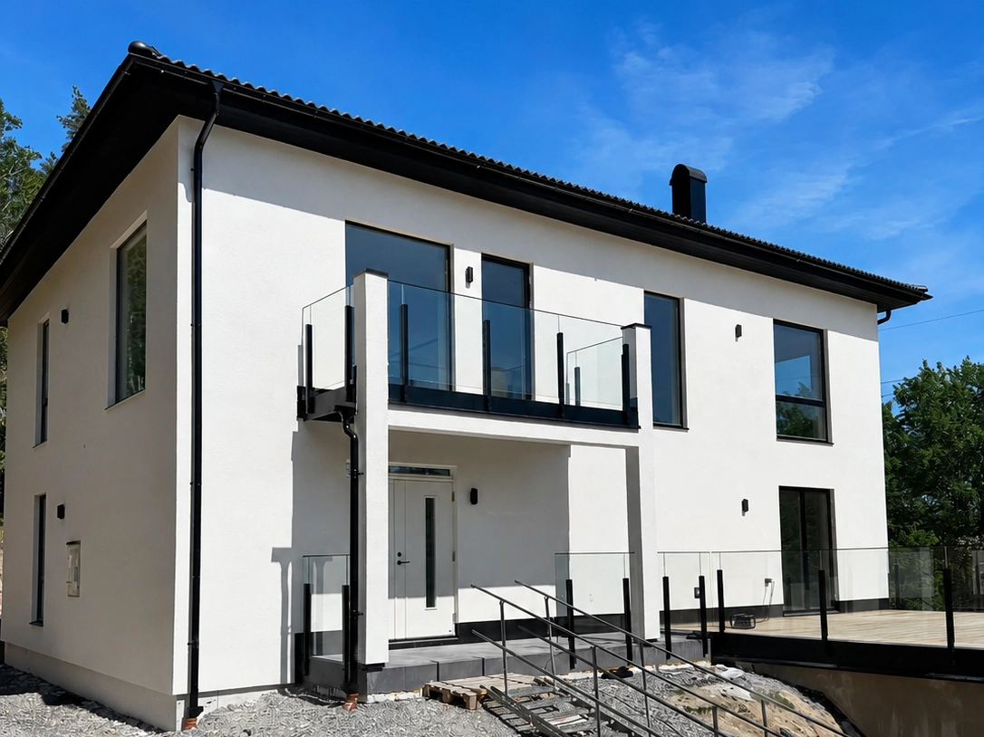 Modern tvåvåningsvilla med glasräcke i svart aluminium vid balkong och terrass.