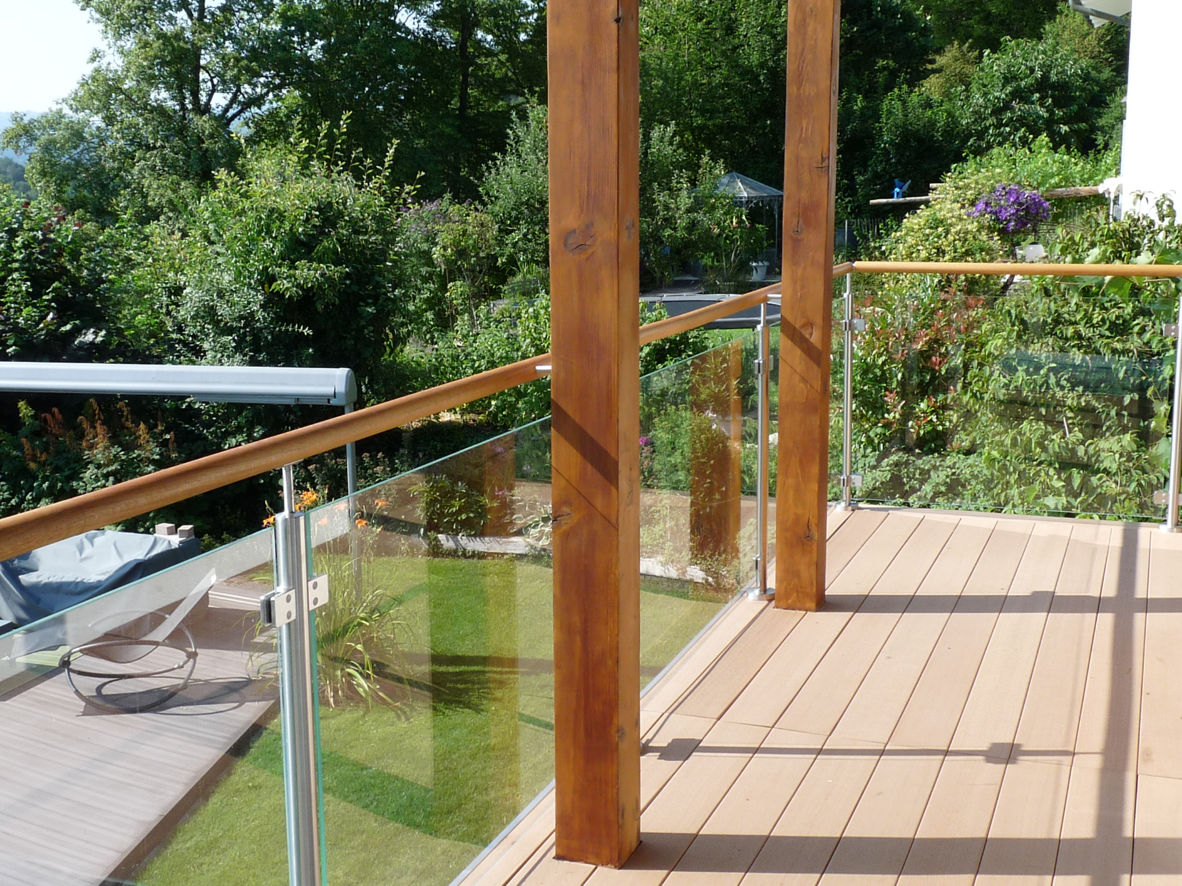 Escalier extérieur avec garde-corps en verre et main courante en bois, adossé à la maison et donnant sur la terrasse.